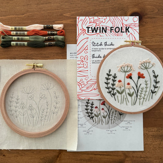 Embroidery hoops with floral patterns and Twin Folk thread on a wooden surface